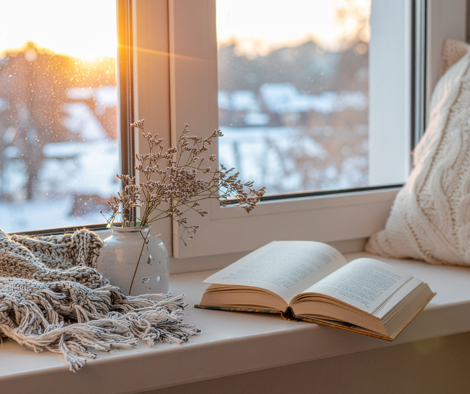 Winter scene out window with book and pillow on window seat