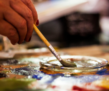 Hand dipping paintbrush into paint